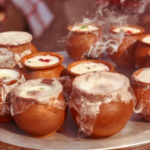 Steaming clay pots of traditional Indian lassi with vibrant garnishes.